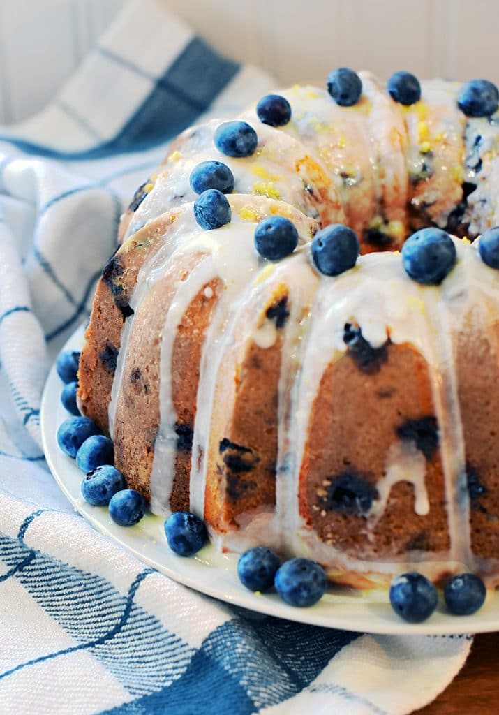 lemon blueberry bundt cake with lemon glaze on a plate topped with blueberries