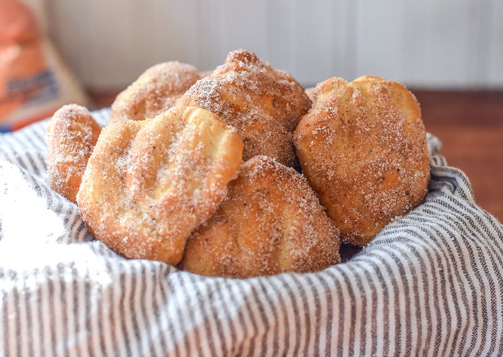 a bowl of bread dough fried in the air fryer and dipped in cinnamon and sugar.