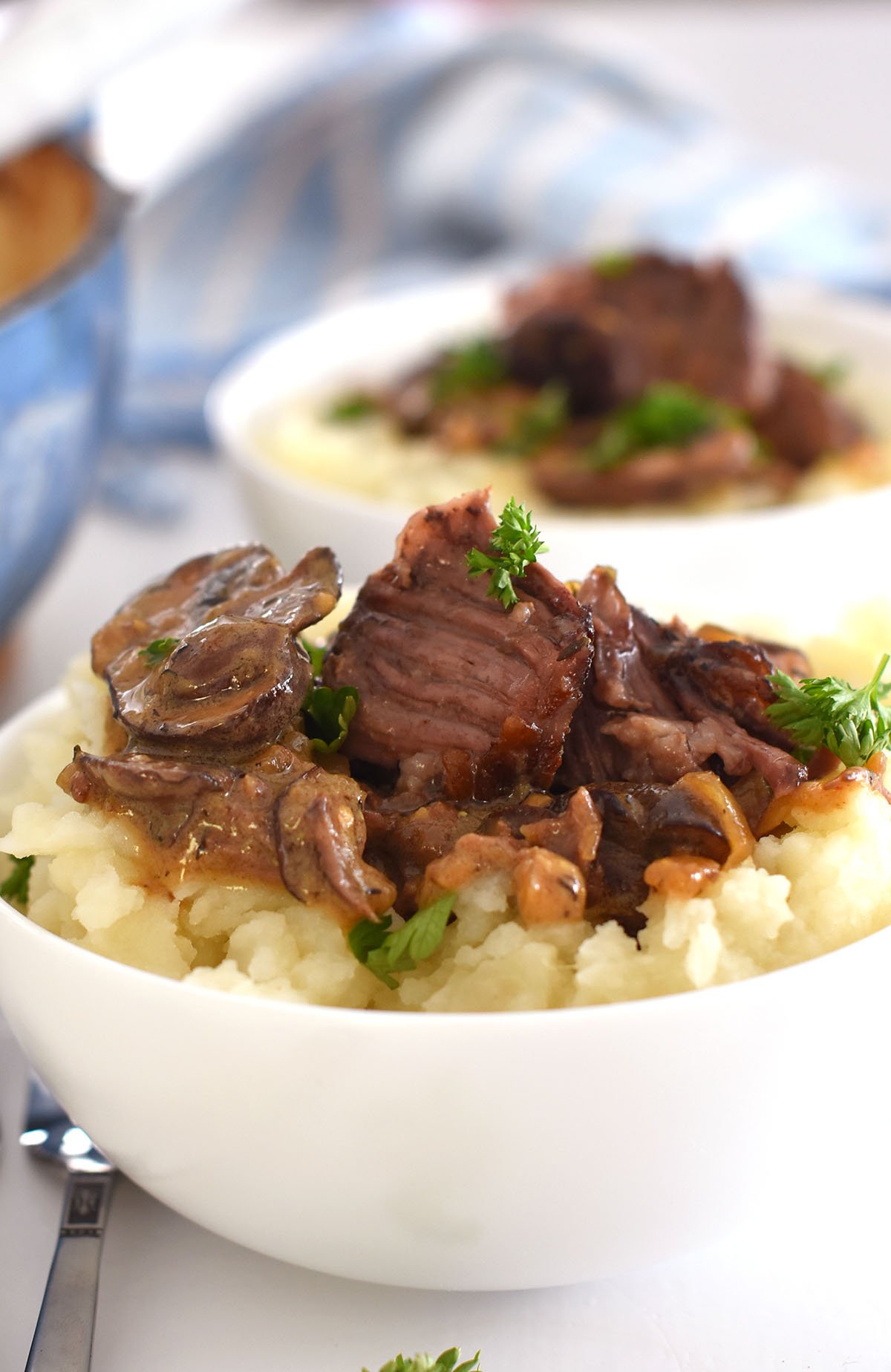 2 bowls of short ribs served over mashed potatoes