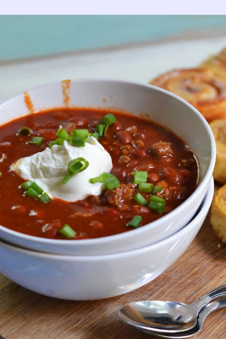 venison chili in a bowl topped with sour cream and green onions
